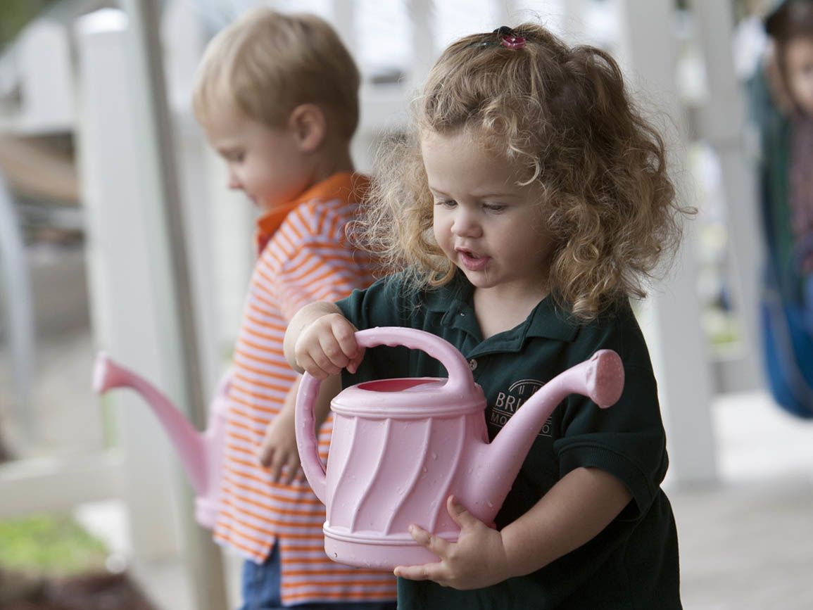 Little girl and boy holding watering cans