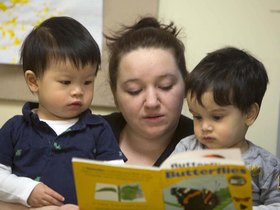 Teacher reading to two toddler boys