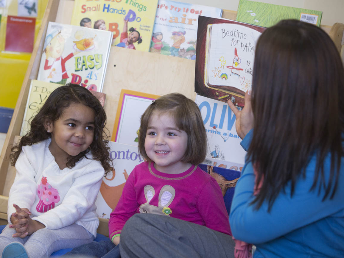 Teacher reading aloud to two preschool aged girls