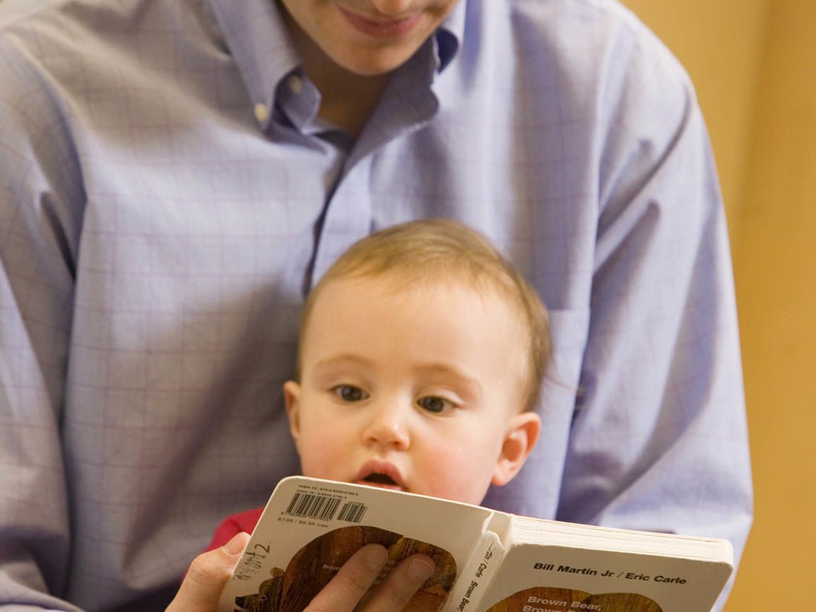 Dad reading to his infant son sitting in his lap