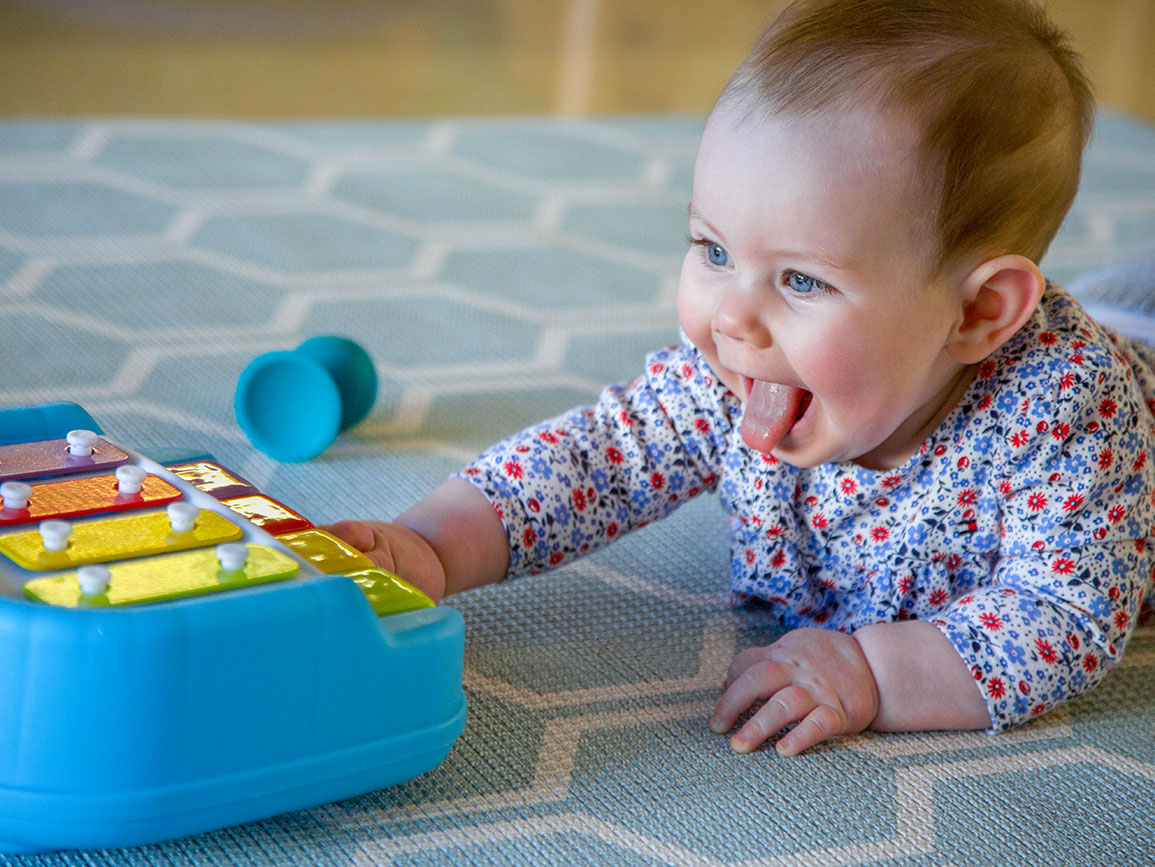 Infant girl on her tummy playing with a xylophone