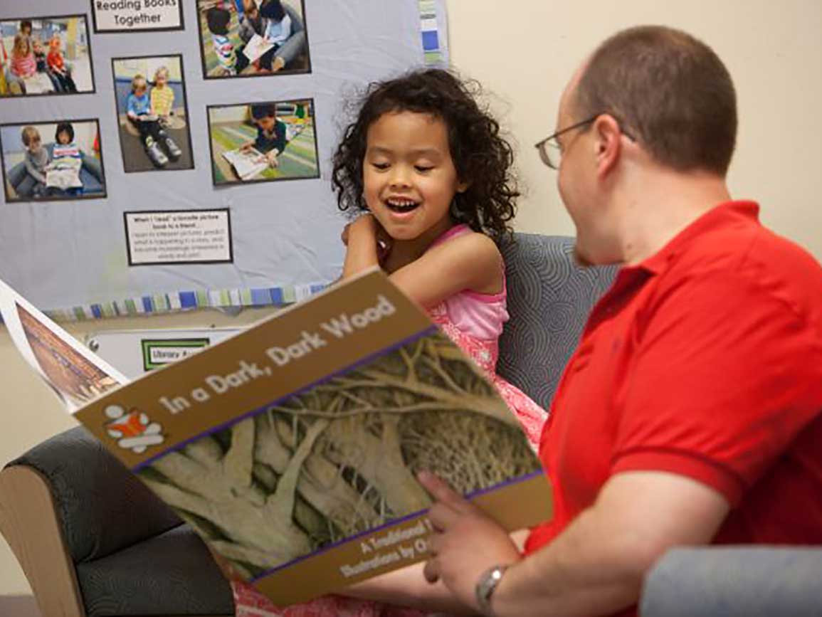 Kindergarten-aged girl reading with dad