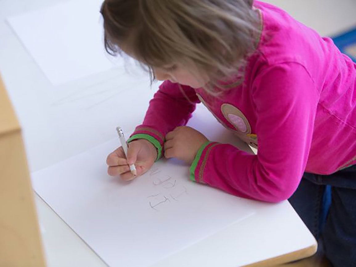 Preschool girl writing on paper