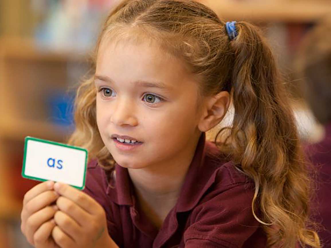 Kindergarten-aged girl holding a flashcard