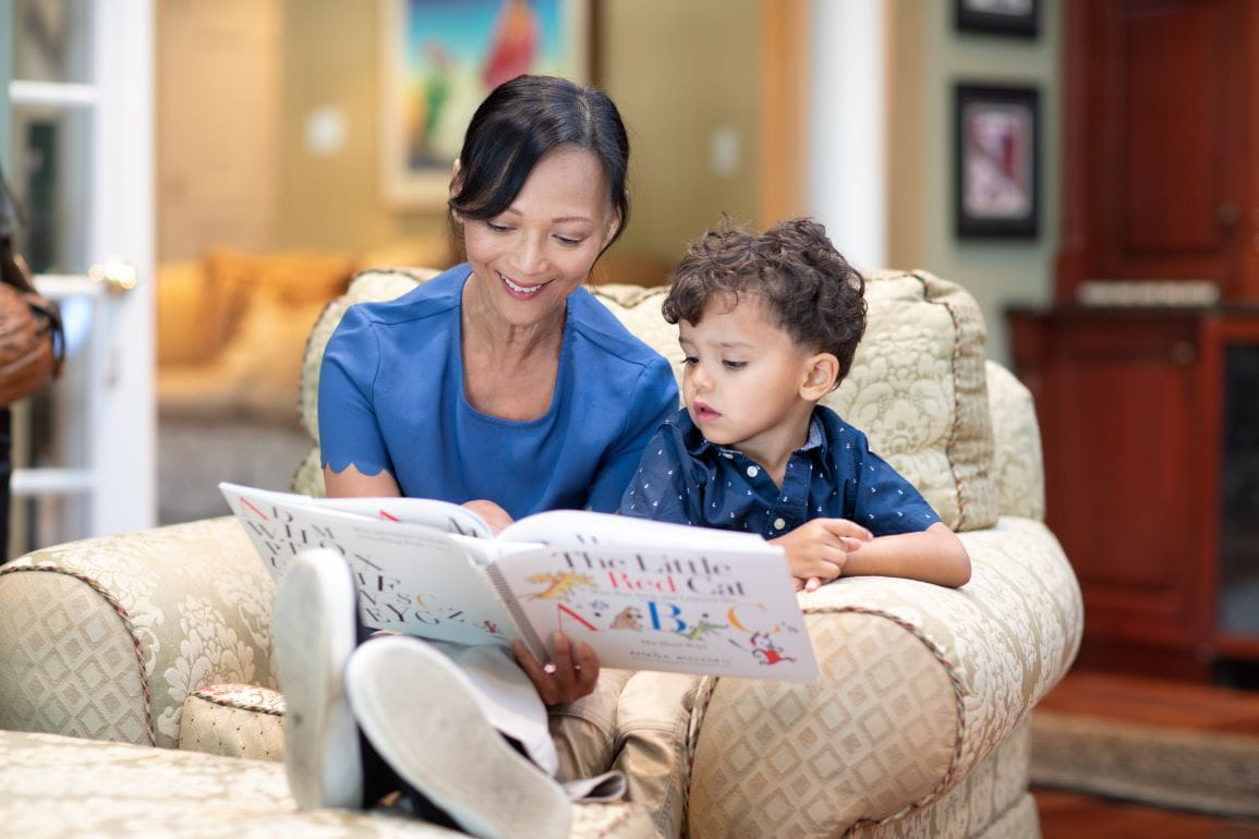 A mother reads to her young boy on a living room chair