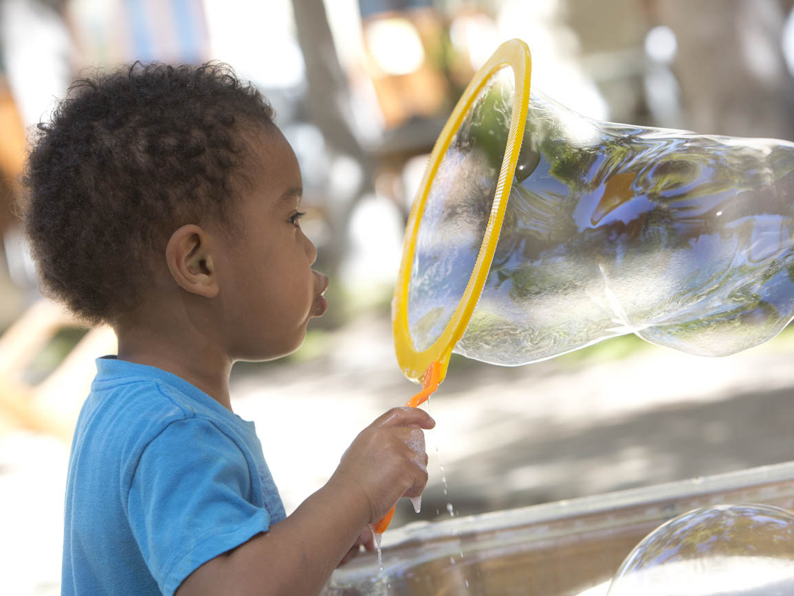 A toddler blowing big bubbles