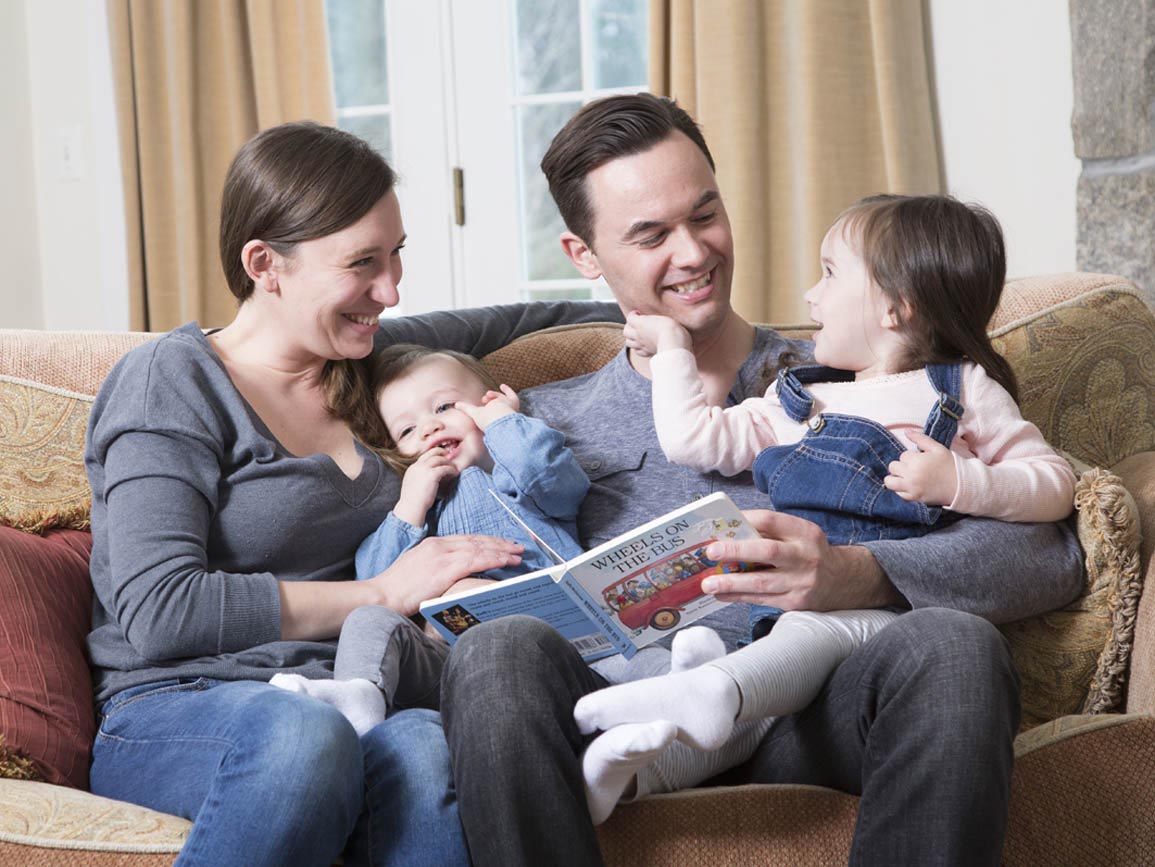 A family on the couch reading a book