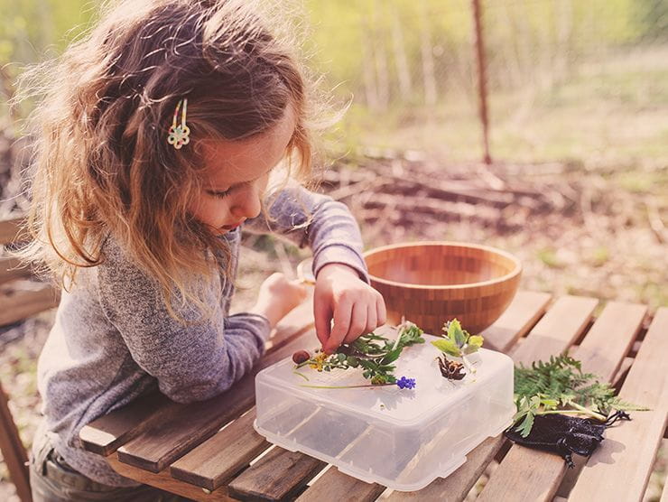 Little girl using plants to make art outside 