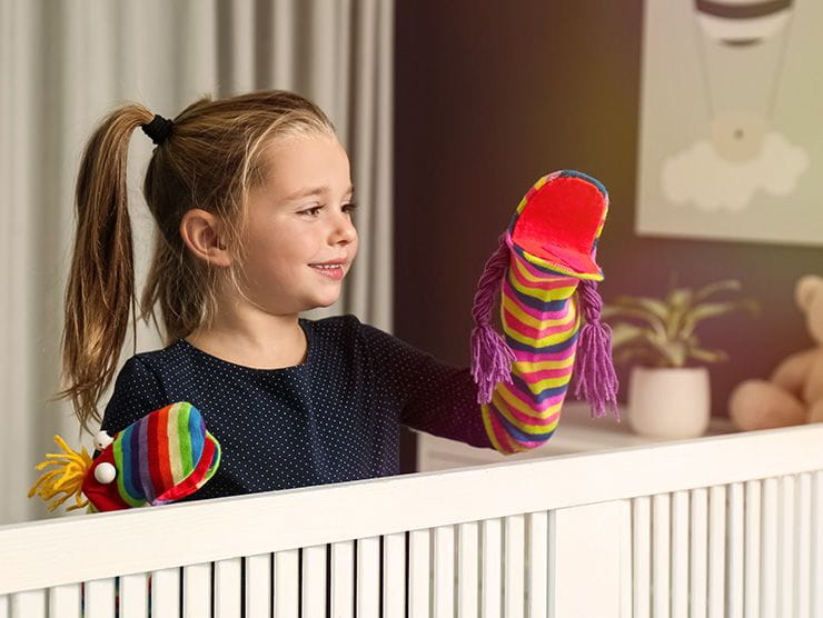 Little girl playing with sock puppets at home 