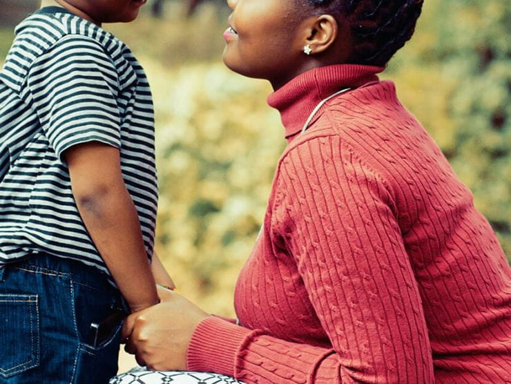 Little boy holding hands with his mother and smiling which represents a positive relationship with an adult 