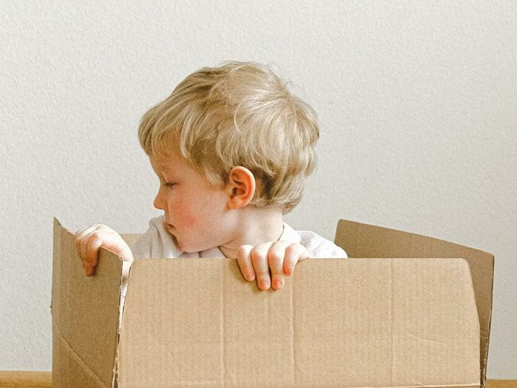 A little boy using his imagination while playing with a cardboard box