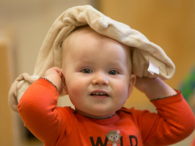 An infant engaging their imagination by using their blanket as a toy at daycare 