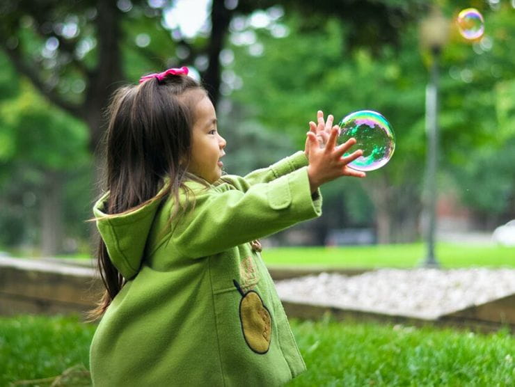 Little girl outside playing and experimenting with bubbles 