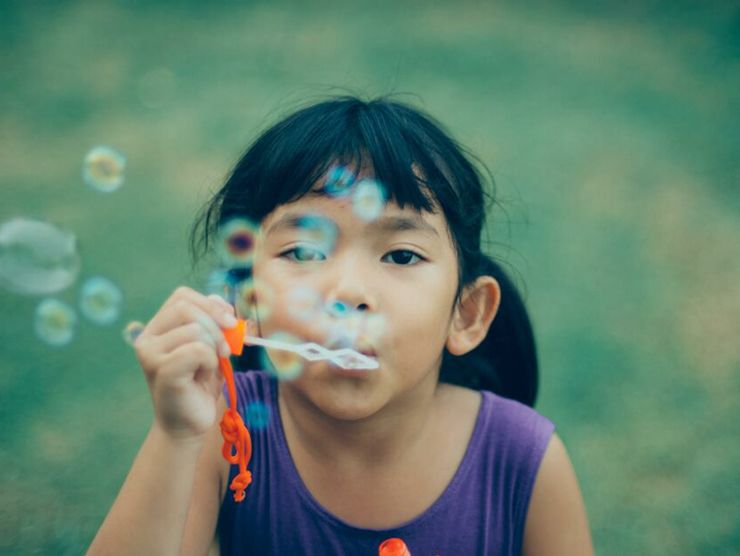 Preschooler blowing bubbles outside of day care