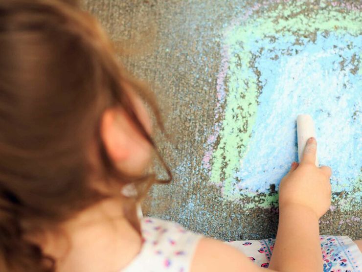 Toddler using chalk to draw on the ground at day care 