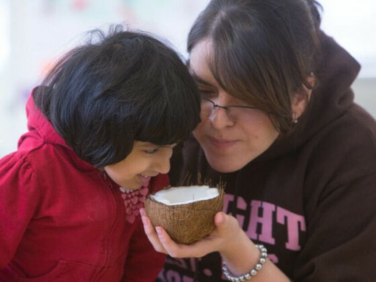Mother and daughter using a coconut to cook healthy recipes at home