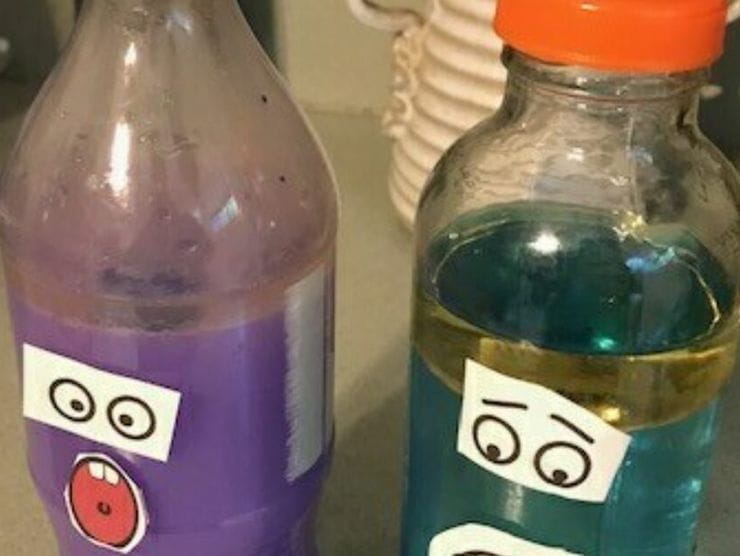 Bottles with colorful water and paper faces taped to them 