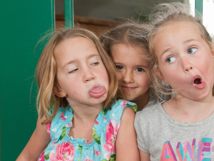 Three toddlers making silly faces during playtime at day care 