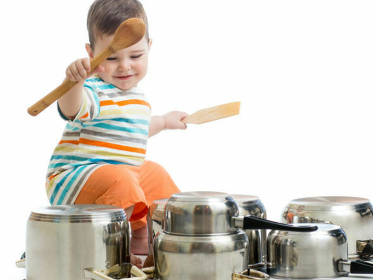 Toddler using pots and pans as drums to make music at home