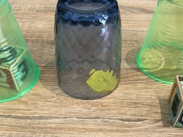 Translucent cups face down on counter covering different toys for kids 