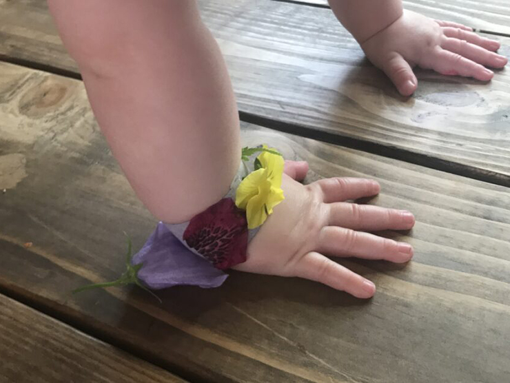 Infants hand with a bracelet made out of flowers 