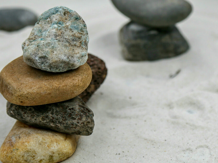 Small rocks stacked on top of each other on sand 