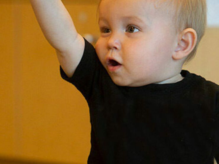Toddler raising his hand in classroom at day care 