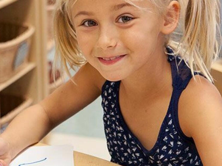 Preschooler smiling while drawing at Bright Horizons day care