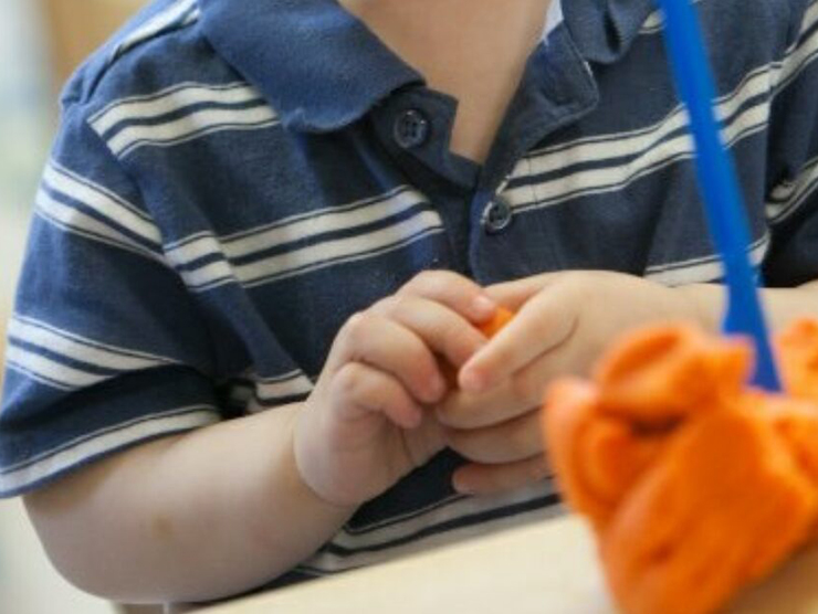 Toddler playing with orange playdough at Bright Horizons day care 