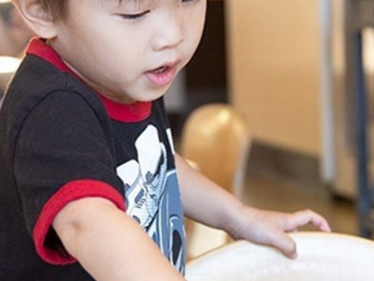 Toddler finger painting with different colors on white paper at home 