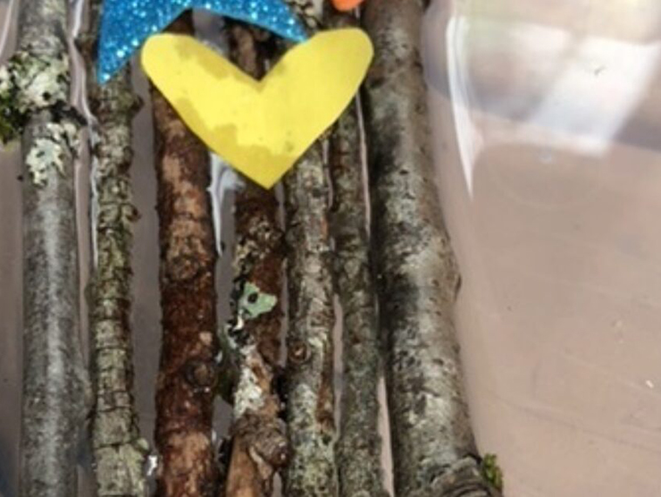 A small raft made out of sticks, string, and decorated with craft supplies at day care 