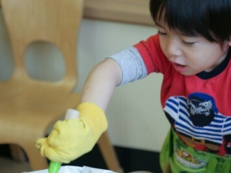 Toddler scooping dirt out of a bucket during an activity at day care 