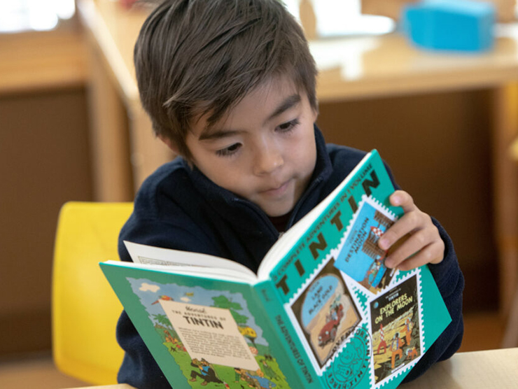 Toddler reading a book in his classroom at day care 