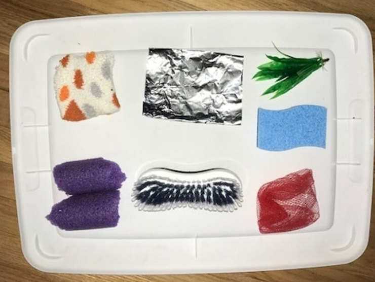 A sensory board made from household items placed onto a flat surface 