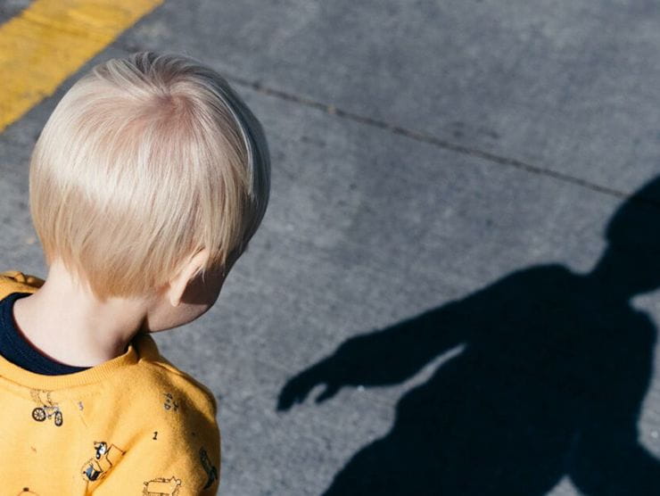 Toddler staring at his shadow on the sidewalk at day care