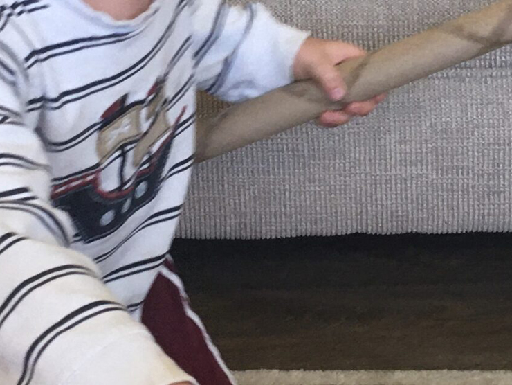 Toddler using a paper towel roll as a toy at home 