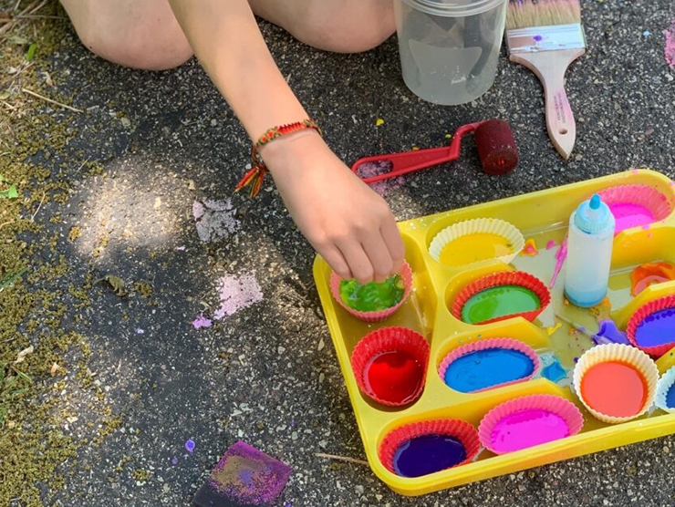 Child painting the sidewalk outside at day care 