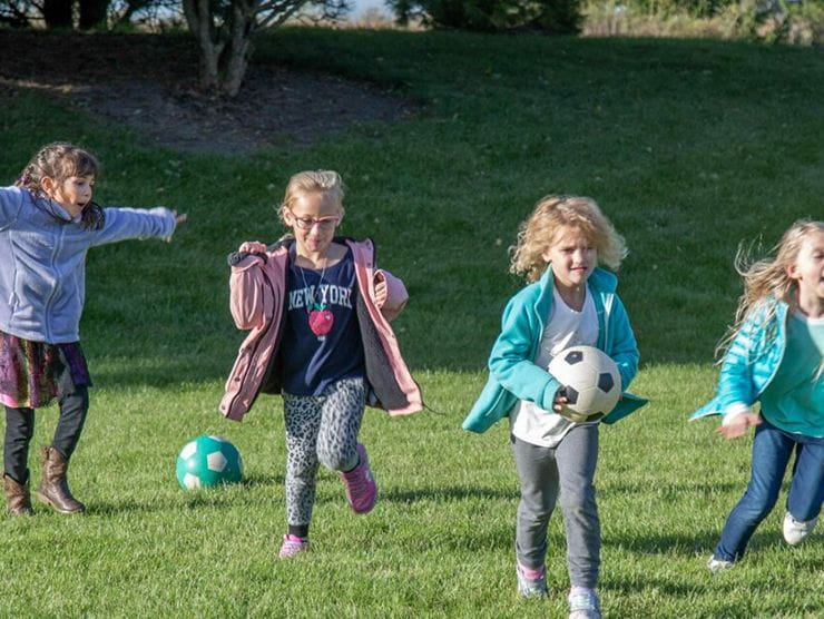 Children running on field outside together at day care 