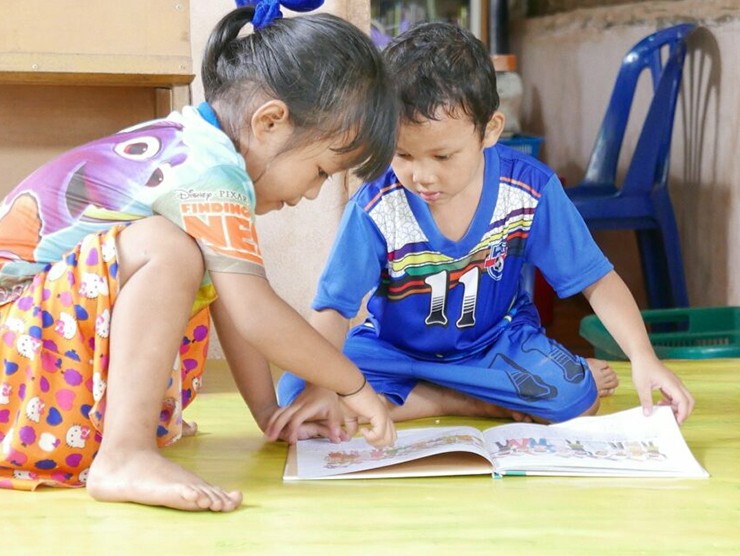 Two toddlers readying a book together at Bright Horizons day care 