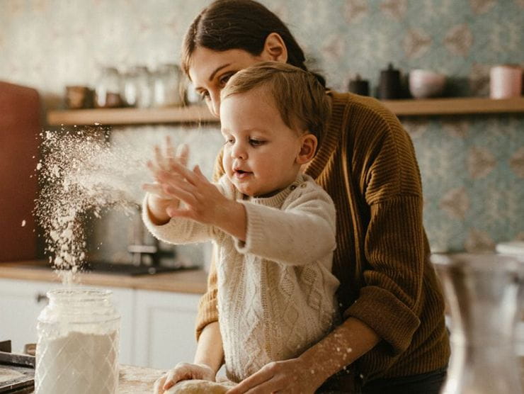 Young child with mother playing with flour at home
