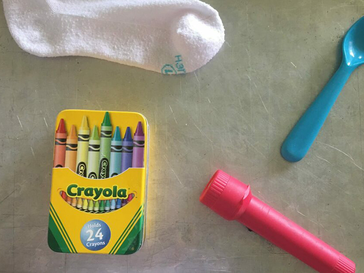 A sock, spoon, flashlight, and box of crayons on a cookie sheet for memory game 