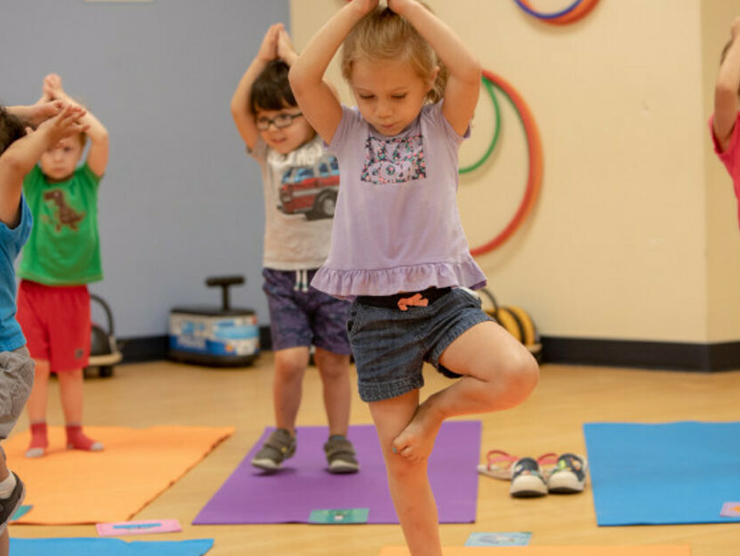 Child doing yoga at daycare while learning about self care with her peers 