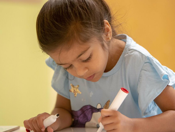 A young girl creating a drawing with markers at daycare 