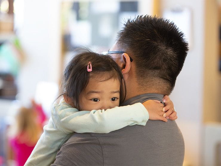 Father in suit holds young daughter reassuringly and explains current events