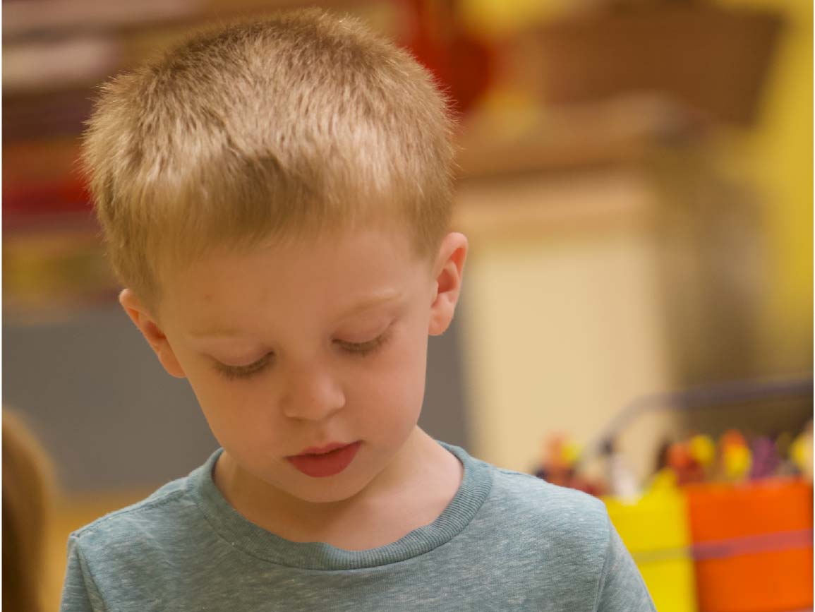 Child looking down at pine cone