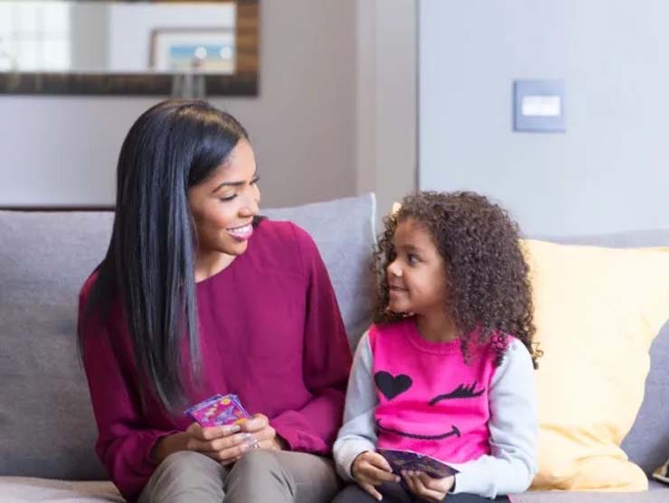 Mother and daughter smile at each other in the living room