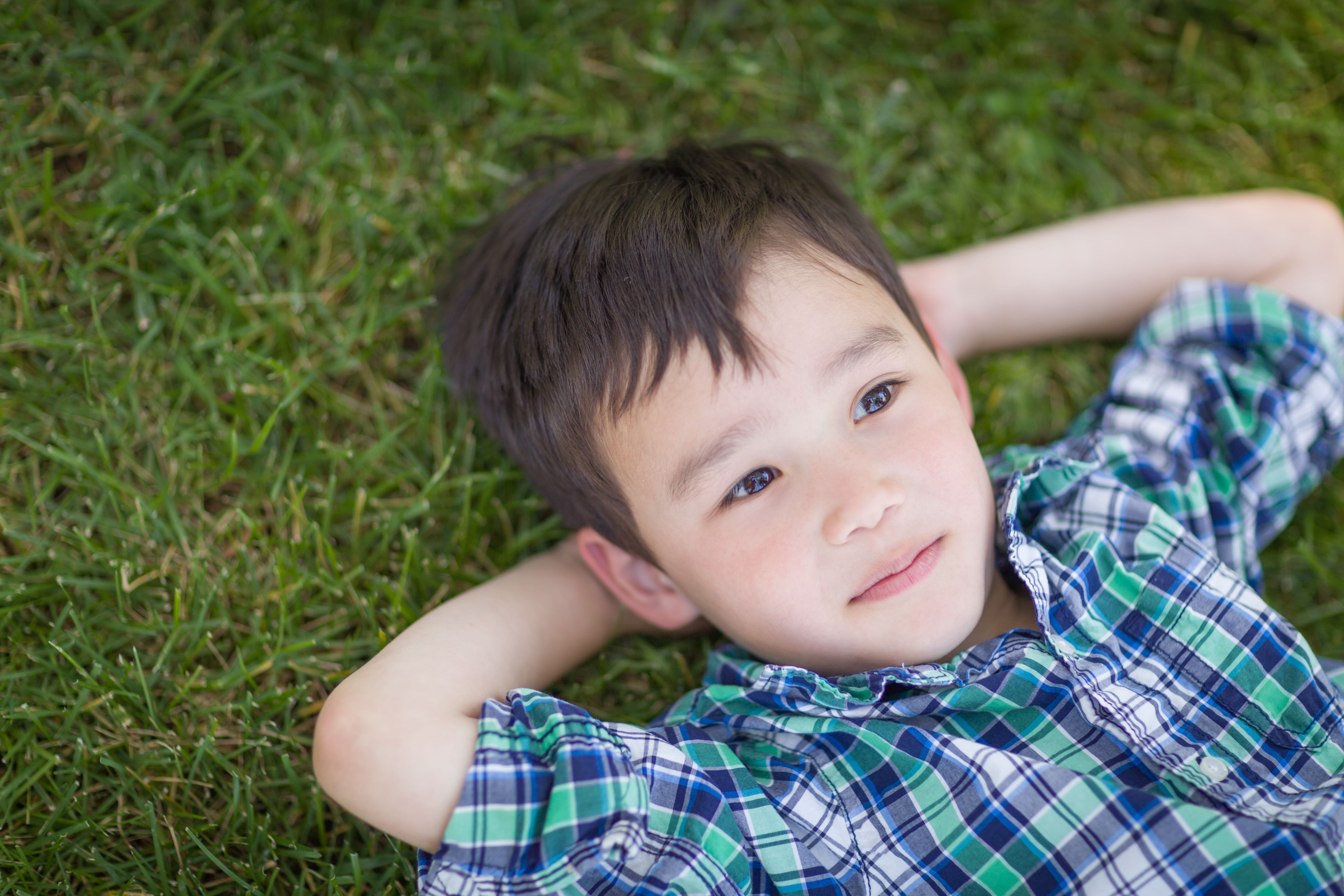 A child laying down on the grass looking up at the sky