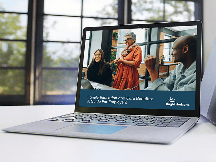 A laptop with an image on the screen of three co-workers collaborating at their office