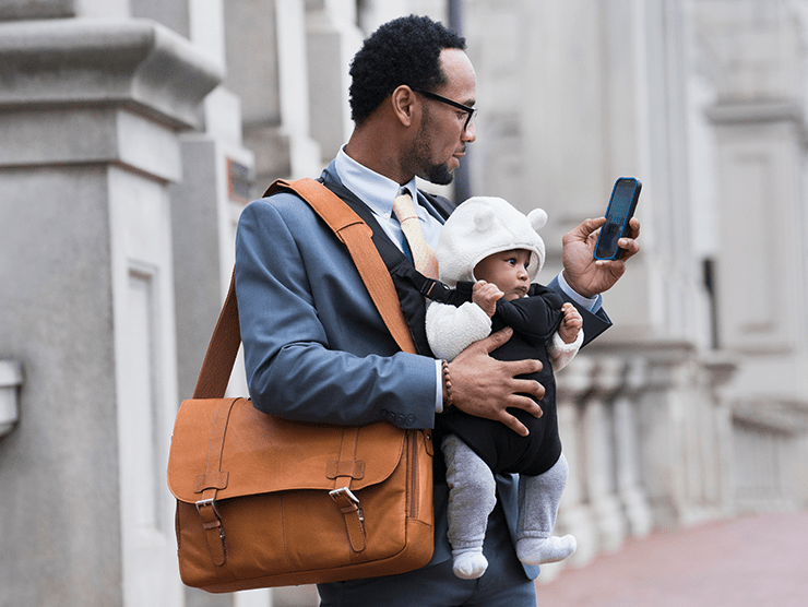 A young professional father with a laptop bag on his shoulder and a baby in front of him 