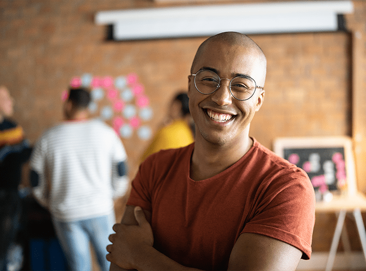 Man with glasses smiling as he's standing in his company office